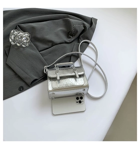 Detail of silver metallic textured crossbody bag with metal studs and top handle