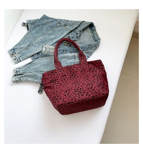 Flat lay of a large burgundy leopard print tote bag paired with a blue denim jacket
