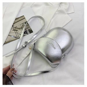 Close-up of the silver metallic saddle bag featuring a unique oval shape and fashion text