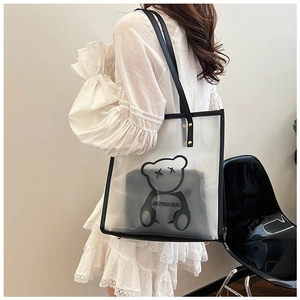Detailed view of clear PVC tote bag with black bear print and inner pouch on a chair