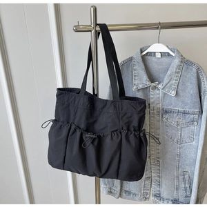 Detailed view of black nylon tote bag featuring functional drawstring utility pockets