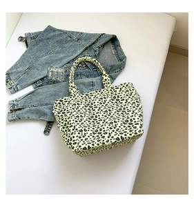 Flat lay of a leopard print canvas tote bag styled with denim jacket on white surface