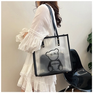Detail view of model carrying a large waterproof tote bag with cartoon bear and inner pouch