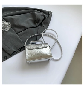 Top-down view of silver metallic messenger bag with protective base studs and strap