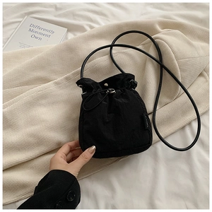 Close-up of black nylon drawstring bucket bag with metal buckle and slim shoulder strap