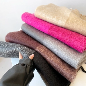 Close-up of stacked soft mohair scarves in multiple colors showing plush knit texture