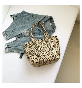 Detailed top view of a leopard print canvas tote bag with reinforced handles and denim accents