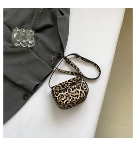 Macro shot of stylish leopard print mini bag with smooth leather strap on white surface