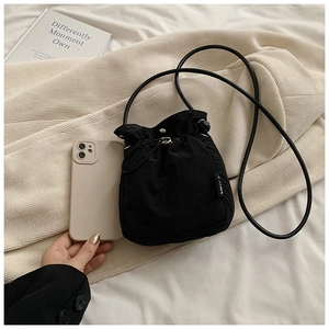 Mini black nylon drawstring bucket bag shown next to a smartphone for size reference