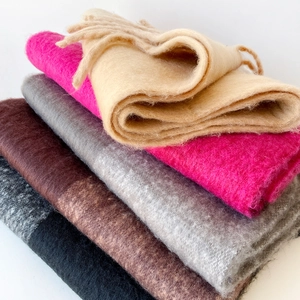 Close-up of stacked colorful mohair scarves showing soft brushed texture and tassel edge