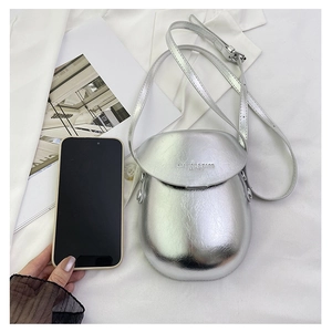 Silver mini saddle bag next to a smartphone showing its compact and portable size