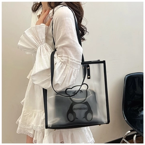 Detailed side view of the transparent PVC tote bag with black trim on a fashion model