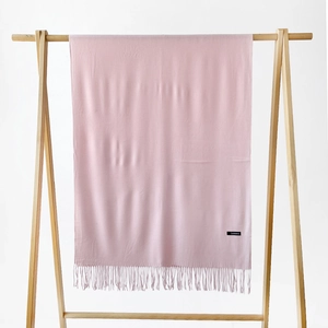 Close-up of light pink cashmere scarf with fine tassel fringe on a wooden hanger