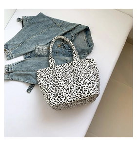 Close-up of leopard print canvas handbag paired with a denim jacket on white background