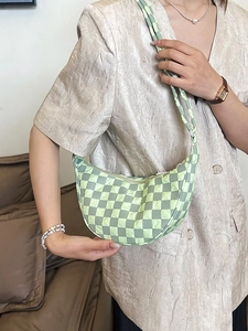 Borsa a triangolo trapuntata a scacchi verdi indossata da una modella in interno caldo