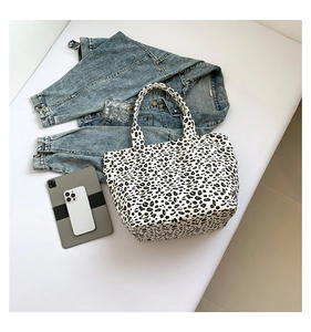 Detailed flat lay of leopard print canvas tote bag with fashion accessories on desk