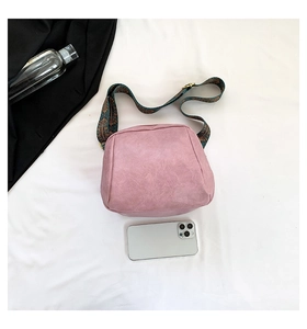 Detailansicht einer rosa Wildledertasche mit breitem ethnischem Schultergurt