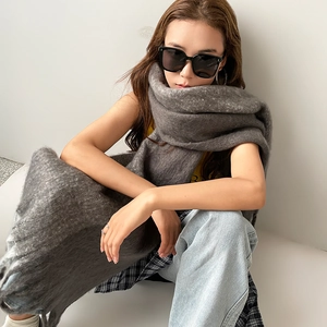 Close-up detail of dark grey mohair scarf texture with elegant fringed edges on a model