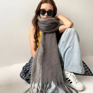 Detailed view of dark grey mohair scarf featuring long tassels and soft warm fuzzy texture