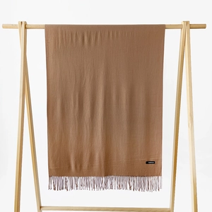 Detail shot of caramel brown cashmere scarf with fine fringe tassels and brand label