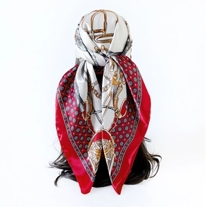 Close-up of equestrian print satin scarf tied on hair with gold chains and red horseshoe