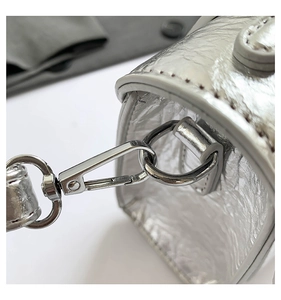 Detail of silver metallic textured leather bag with polished metal D-ring and lobster clasp