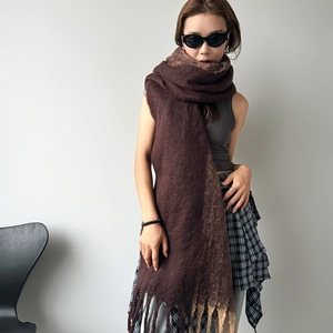 Detail view of thick dark brown mohair scarf with long tassels and soft knit texture