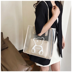 Close-up of clear PVC bear tote with beige inner pouch and gold rivet handles