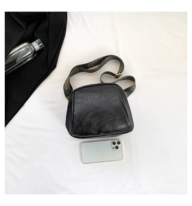 Detailansicht der schwarzen PU-Leder-Tasche mit Ethno-Stickerei-Gurt und Vintage-Textur