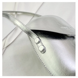 Close-up of silver metallic crossbody bag featuring cracked texture and metal rivets