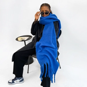 Detailed texture of Klein Blue knitted scarf with thick fringe tassels on model