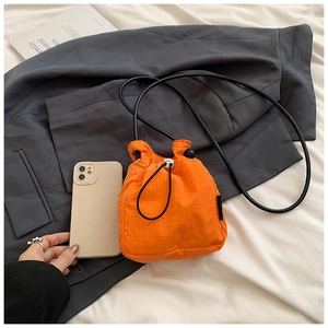 Detail view of mini orange nylon drawstring bucket bag showing compact size and texture