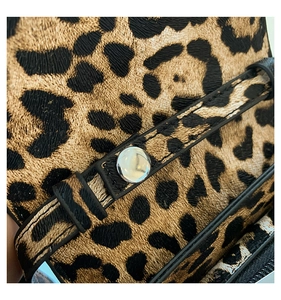 Macro shot of leopard print embossed leather texture with a silver metallic snap button