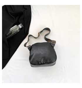 Detail der schwarzen PU-Muscheltasche mit böhmischem Jacquard-Gurt und Metallschnalle