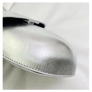 Macro shot of silver cracked leather texture and fine stitching on a metallic shoe
