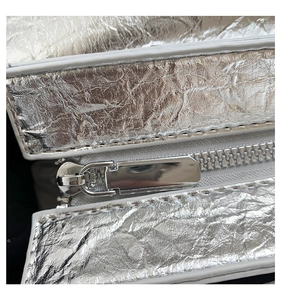 Detailed macro view of silver crinkle textured fabric and polished metal zipper on bag