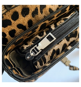 Close-up of leopard print shoulder bag with silver zipper and black stitching details