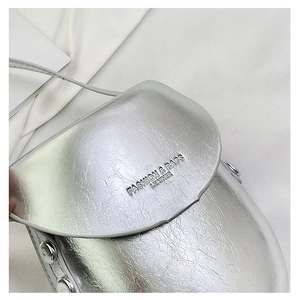 Detailed macro view of silver metallic crossbody bag with engraved fashion text and rivets