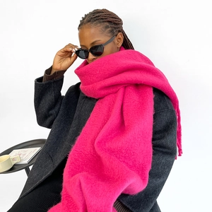 Dettaglio di sciarpa rosso rosa stile mohair con lunghe nappe e consistenza morbida