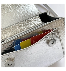 Detail of silver metallic bag featuring card slots and magnetic snap button closures