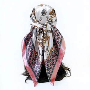 Detail of pink satin square scarf with chain print and polka dots worn as a headscarf