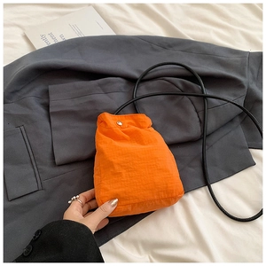 Detail of orange checkered mini nylon bag with drawstring strap and silver snap button