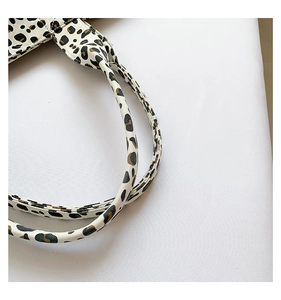 Close-up detail of leopard print tote bag with brown faux leather handles and fine texture