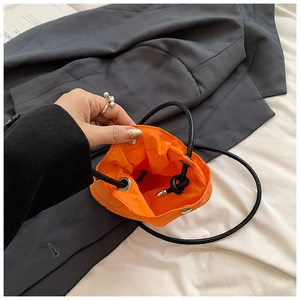 Detail view of bright orange mini nylon bucket bag with drawstring and snap closure