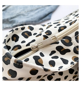 Detailed macro view of leopard print canvas bag showing a silver metal zipper closure