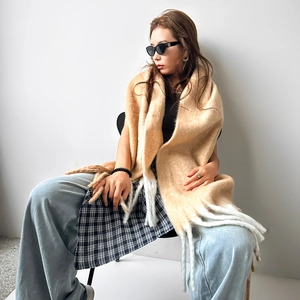 Close-up of thick mohair scarf with camel color blocks and white tassels on model