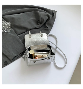 Detailed view of silver metallic messenger bag with crackle texture and interior storage