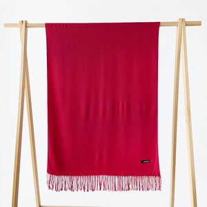 Detailed view of dark red cashmere scarf with fringe hem and sewn brand label