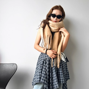 Detailed close-up of camel mohair knit scarf featuring long fringe and soft texture