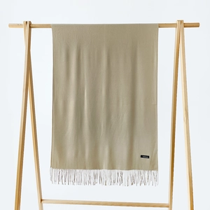 Detail of soft beige cashmere scarf featuring elegant fringe and woven material label